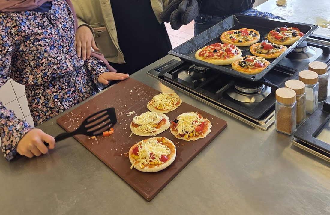 Leerlingen maken hun eigen mini-pizza's tijdens de workshop
